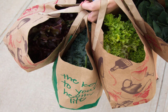 Paper bags of colorful green leafy vegetables.